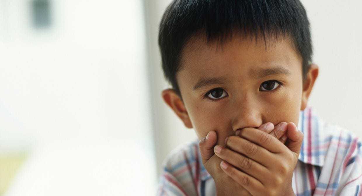 Young boy covering his mouth
